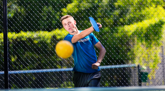 Boy hitting pickleball with paddle